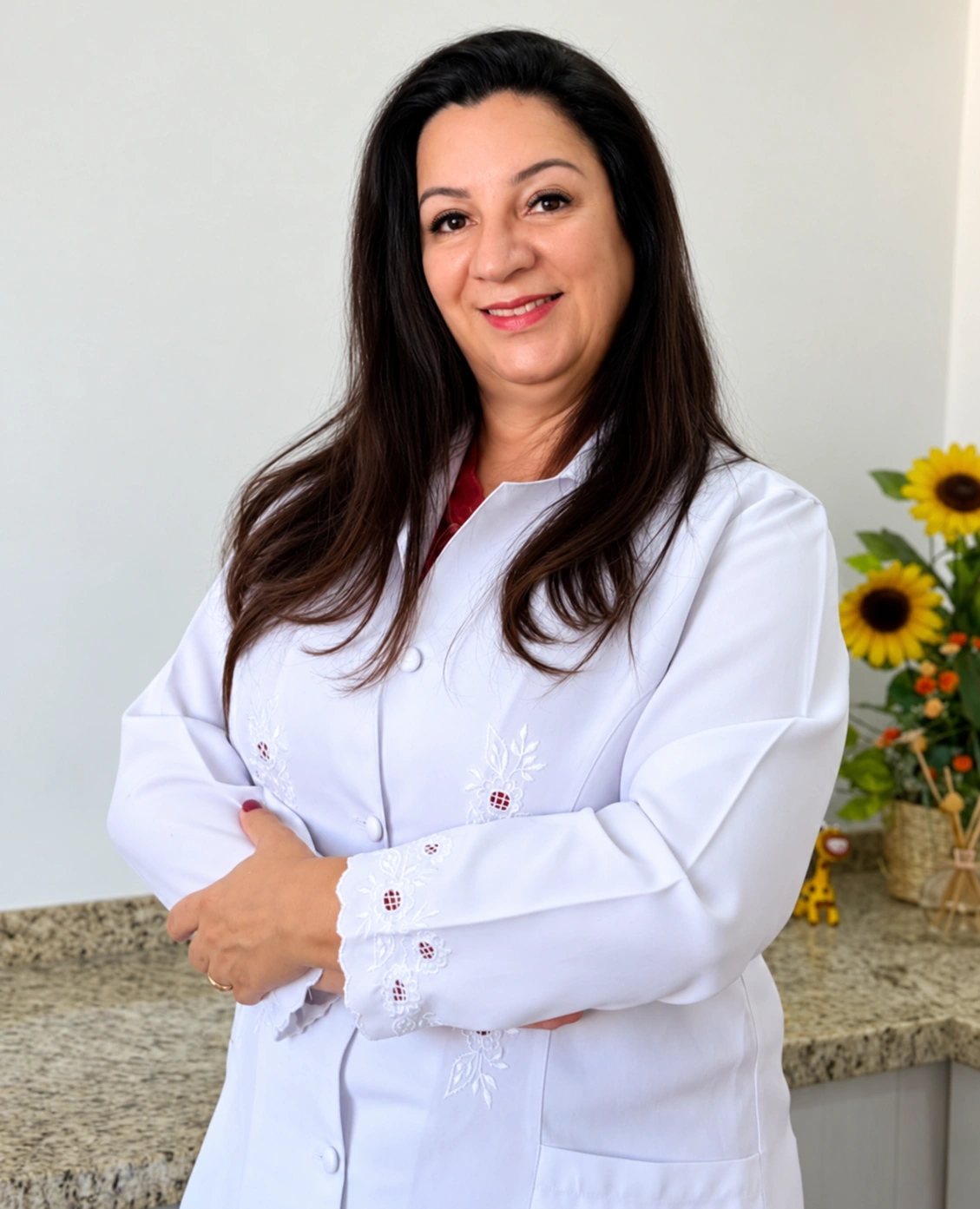 Dra. Giovana Matos sorrindo, de jaleco e braços cruzados no consultório